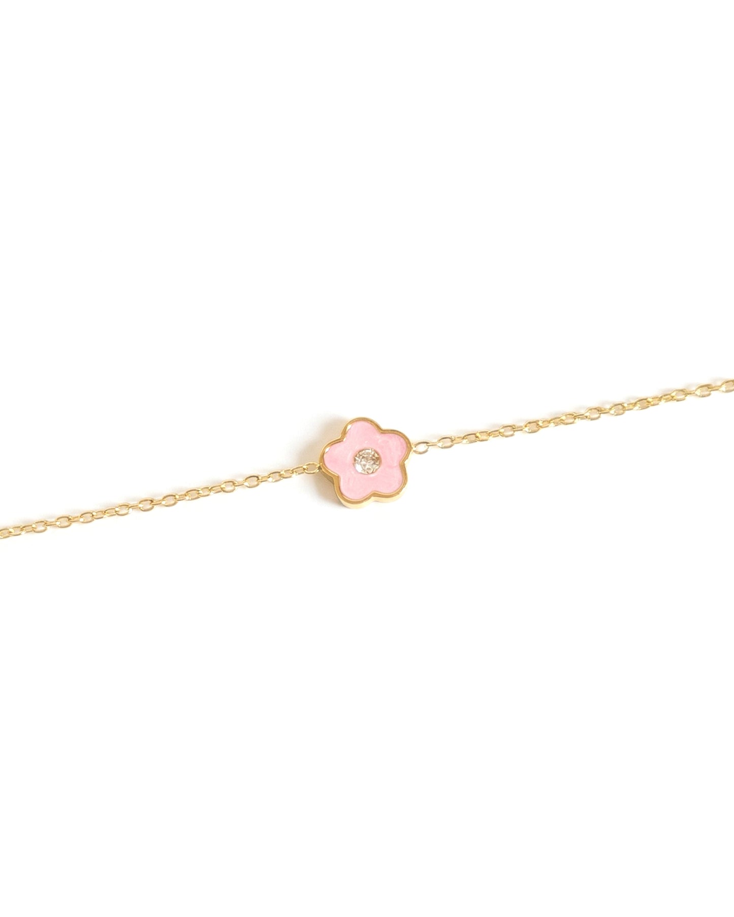 Gold bracelet with a pink flower charm on a white background